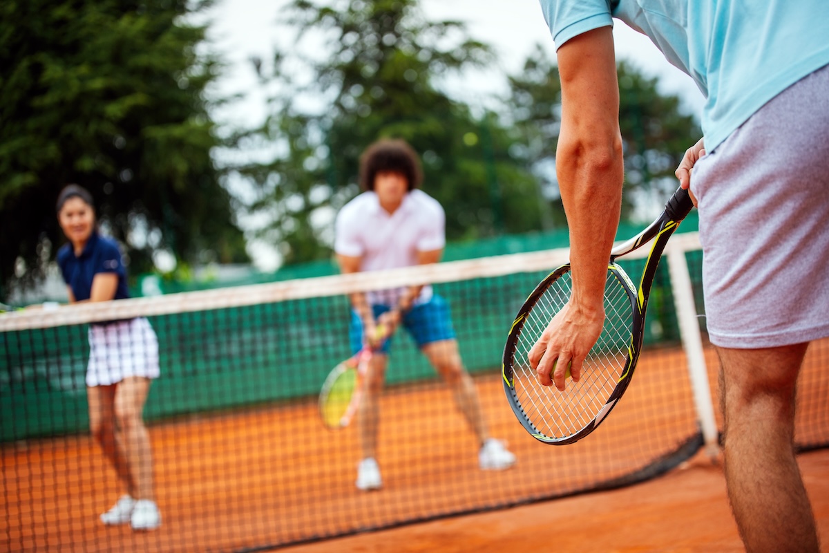 Doubles tennis match on red clay courts