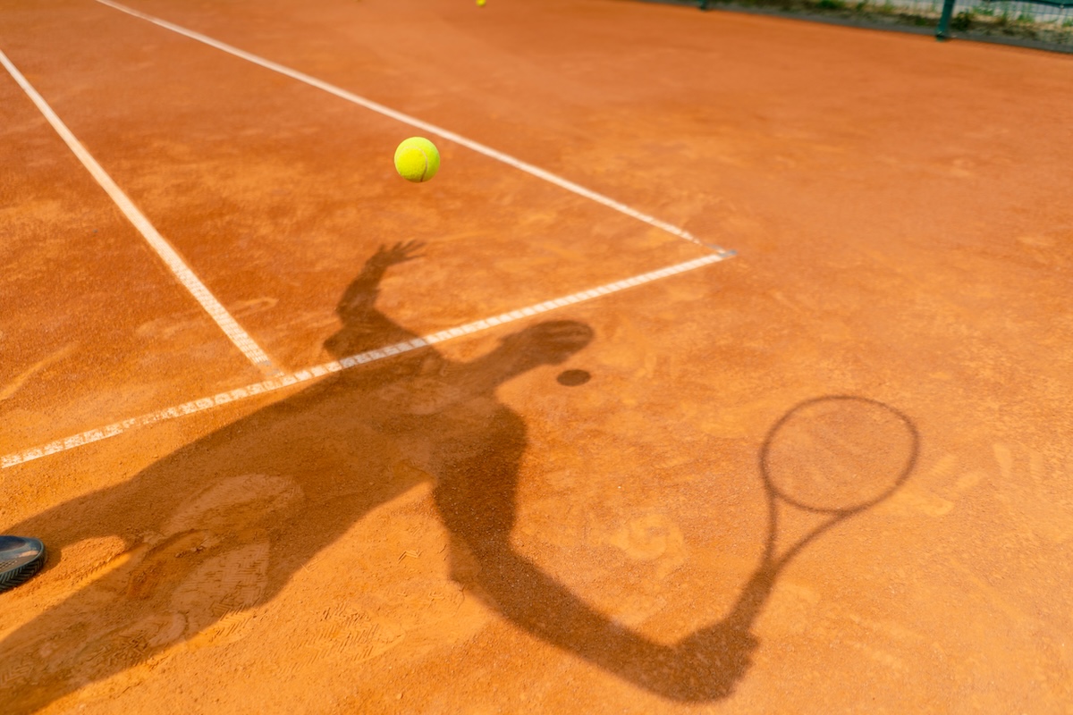 Red clay tennis court with natural lighting at Trailside Tennis Club